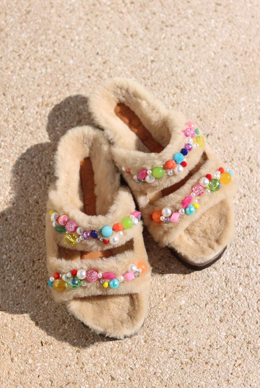Mimi Candy shearling sandals flat lay — shearling double-strap slides with hand-applied multicolour beads and pearls on sand, Alameda Turquesa Portugal