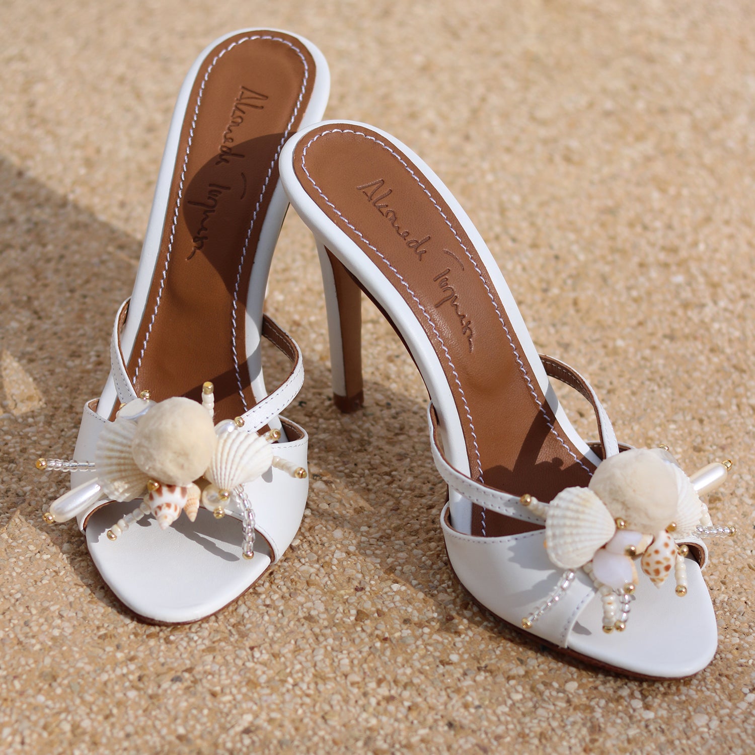 Delphine white leather mules flat lay — natural shell and pearl embellishments on open-toe stiletto heel, handcrafted bridal shoes by Alameda Turquesa Portugal