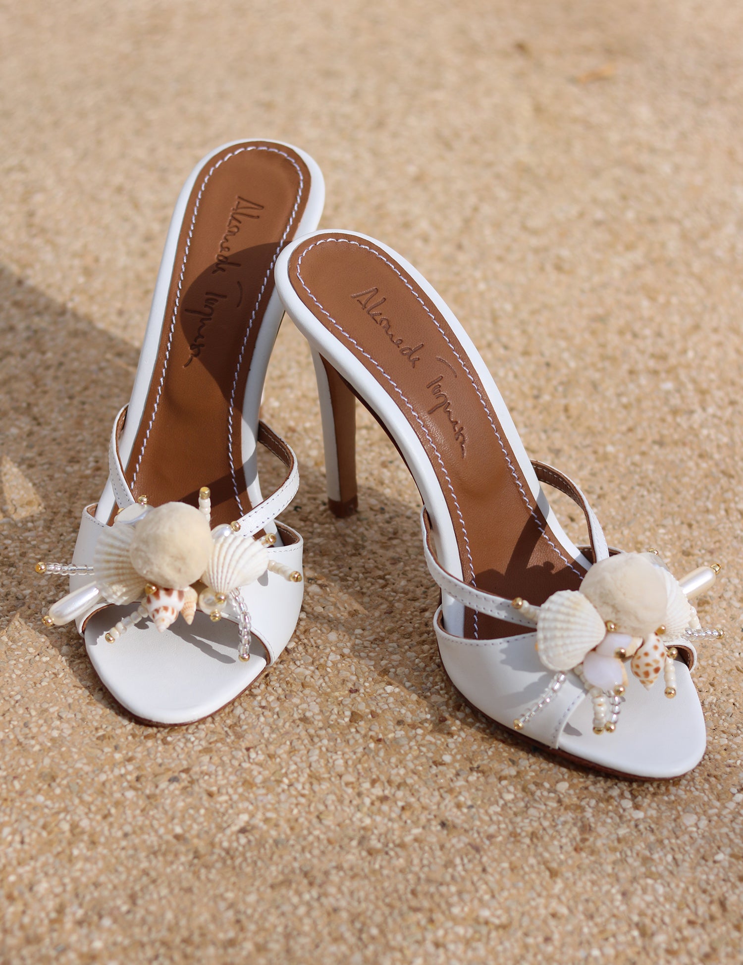 Delphine white leather mules flat lay — natural shell and pearl embellishments on open-toe stiletto heel, handcrafted bridal shoes by Alameda Turquesa Portugal