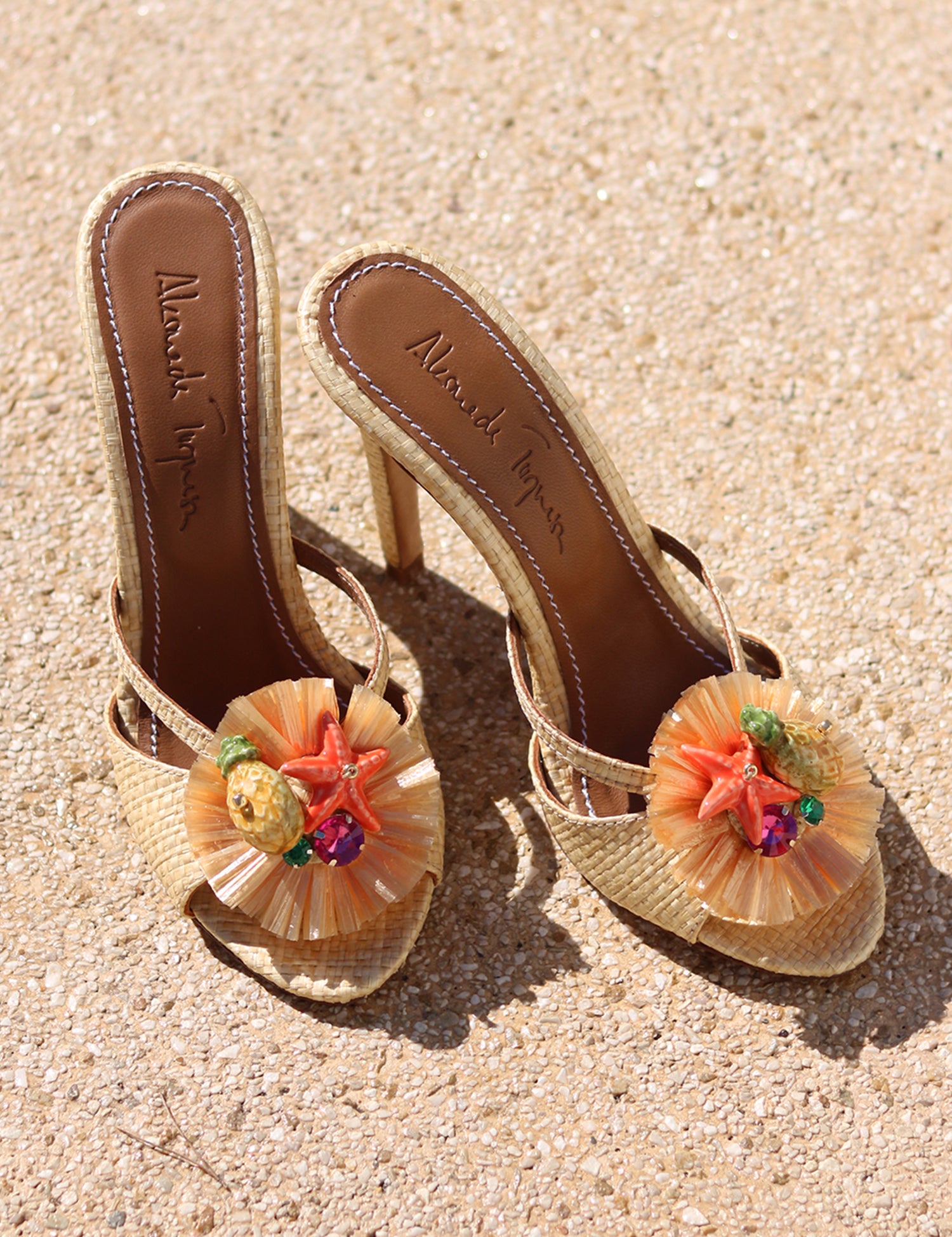 Tutti Frutti raffia mules flat lay on sand — natural raffia stiletto mules with handcrafted starfish and tropical fruit cluster embellishments, Alameda Turquesa insole, handcrafted in Portugal by Alameda Turquesa