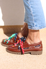 Andie boat shoes side profile — tan leather chunky sole boat shoes with multicolour handcrafted beaded laces in navy, red and teal, worn on body with jeans, handcrafted in Portugal by Alameda Turquesa