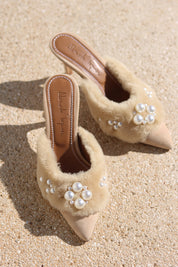 Bella shearling mules flat lay — cream shearling pointed-toe stiletto mules with hand-applied pearl cluster embellishments, shot on sand, handcrafted in Portugal by Alameda Turquesa