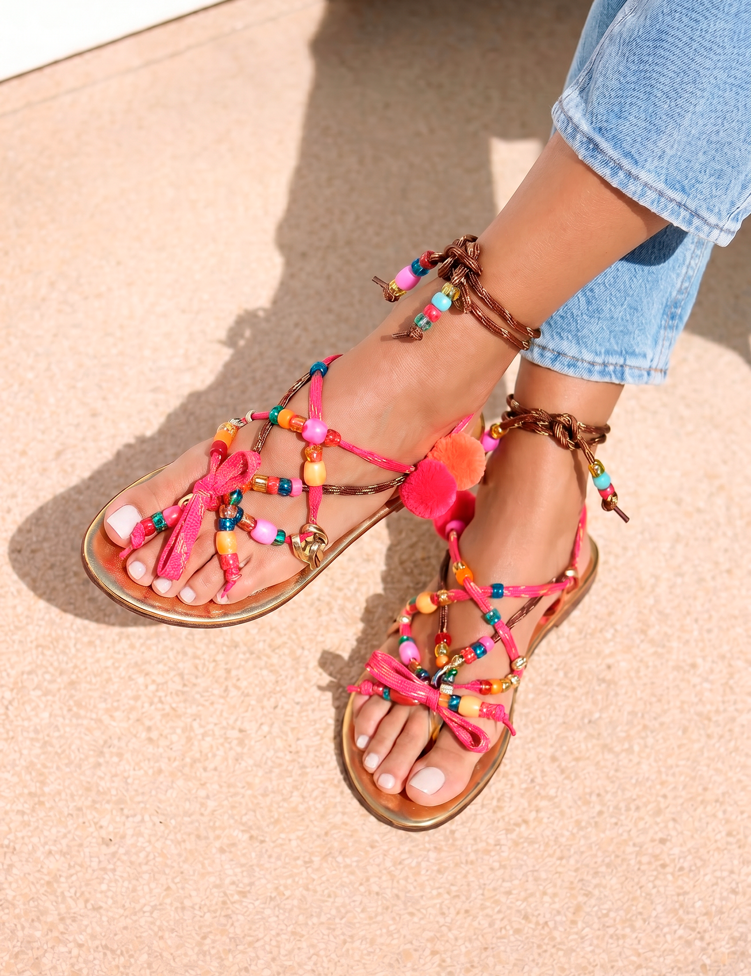 Lilo Gold sandals top view — gold leather flat sandals with multicolour handcrafted beaded straps and pom pom and tassel embellishments in pink, orange, yellow and red, worn on body with jeans, handcrafted in Portugal by Alameda Turquesa