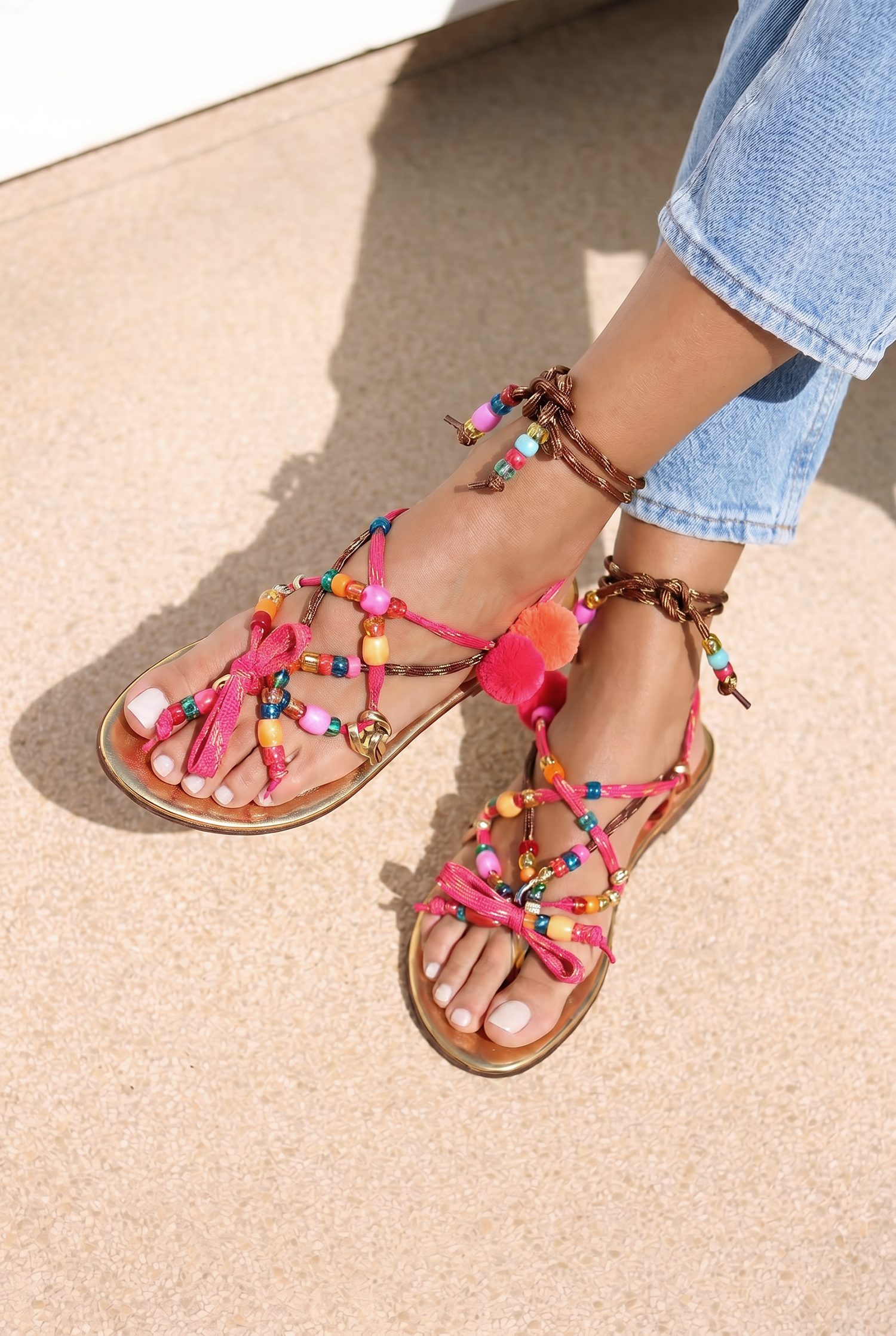 Lilo Gold sandals top view — gold leather flat sandals with multicolour handcrafted beaded straps and pom pom and tassel embellishments in pink, orange, yellow and red, worn on body with jeans, handcrafted in Portugal by Alameda Turquesa