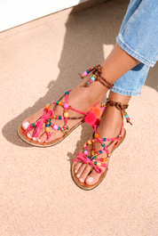 Lilo Gold sandals top view — gold leather flat sandals with multicolour handcrafted beaded straps and pom pom and tassel embellishments in pink, orange, yellow and red, worn on body with jeans, handcrafted in Portugal by Alameda Turquesa