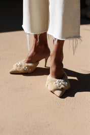 Bella shearling mules pair view — cream shearling pointed-toe stiletto mules with hand-applied pearl cluster embellishments, worn on body with white dress, handcrafted in Portugal by Alameda Turquesa