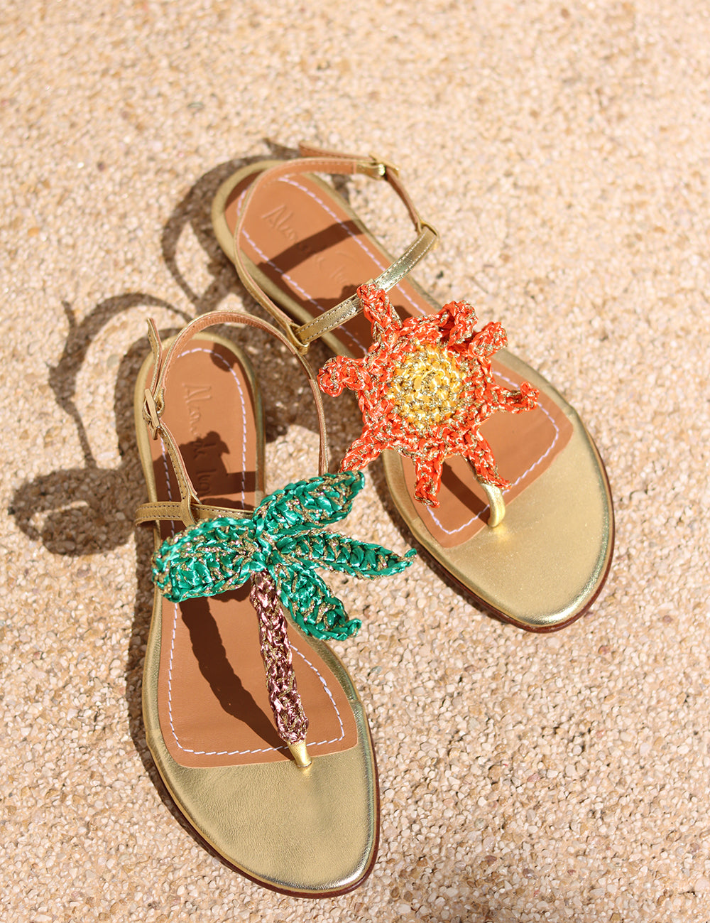 Sunset Dreamer flat sandals flat lay — gold leather thong sandals with handcrafted crochet palm tree and sun motifs, Alameda Turquesa Portugal
