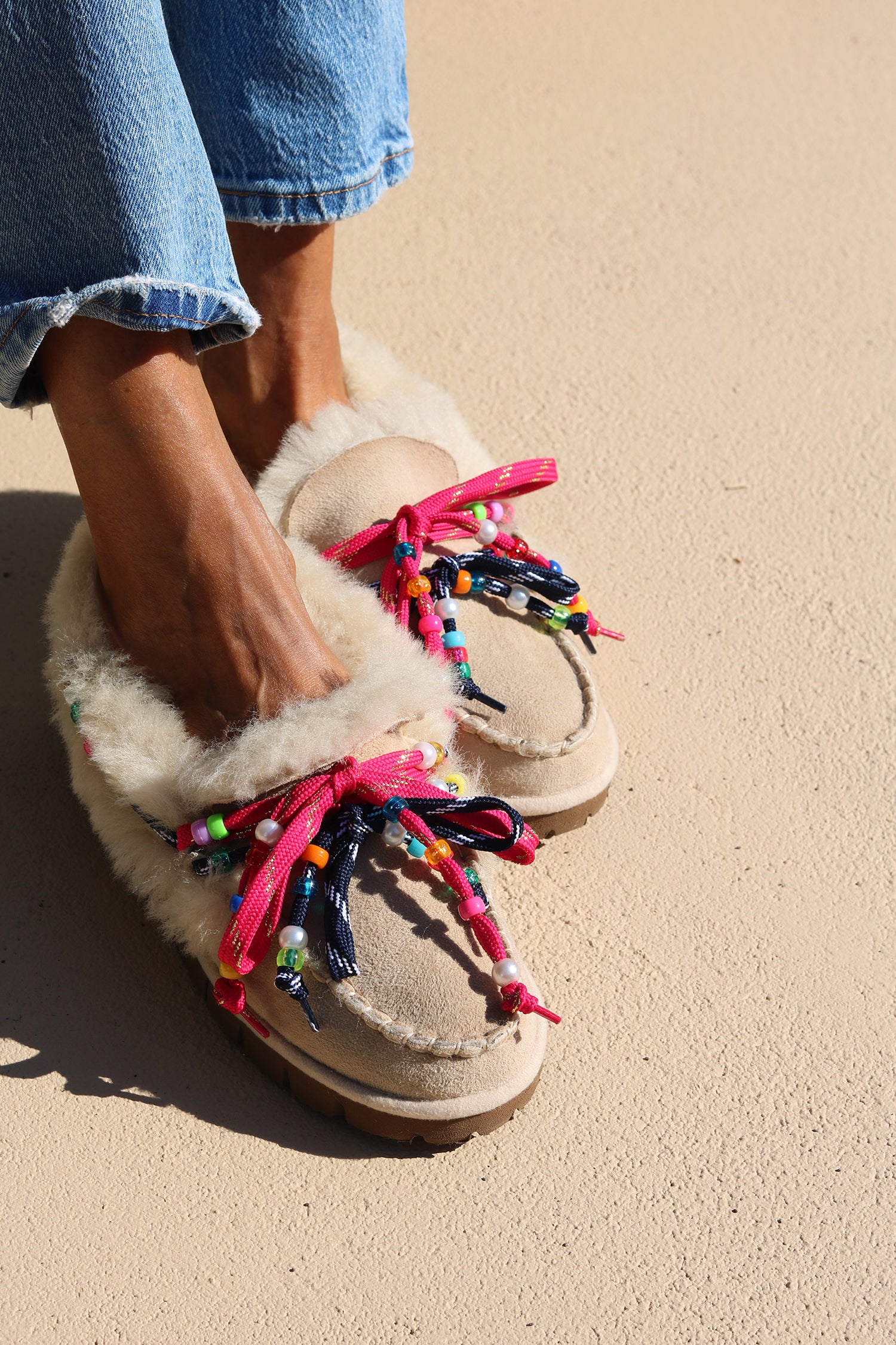 Close-up of Lou shearling moccasins with vibrant pink and navy laces, multicoloured beads, pearl accents and soft genuine shearling.