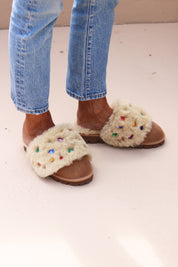 Jasmine flat shearling mule being worn, front view — cream shearling with multicoloured gemstone embellishments, made in Portugal by Alameda Turquesa