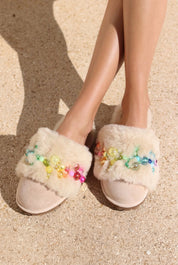 Pinctada Vanilla Rainbow shearling mules front view — ivory shearling mules with handcrafted rainbow pearl embellishments in pink, orange, yellow, green and aqua on sand suede, both feet worn on skin against sandy ground, handcrafted in Portugal by Alameda Turquesa