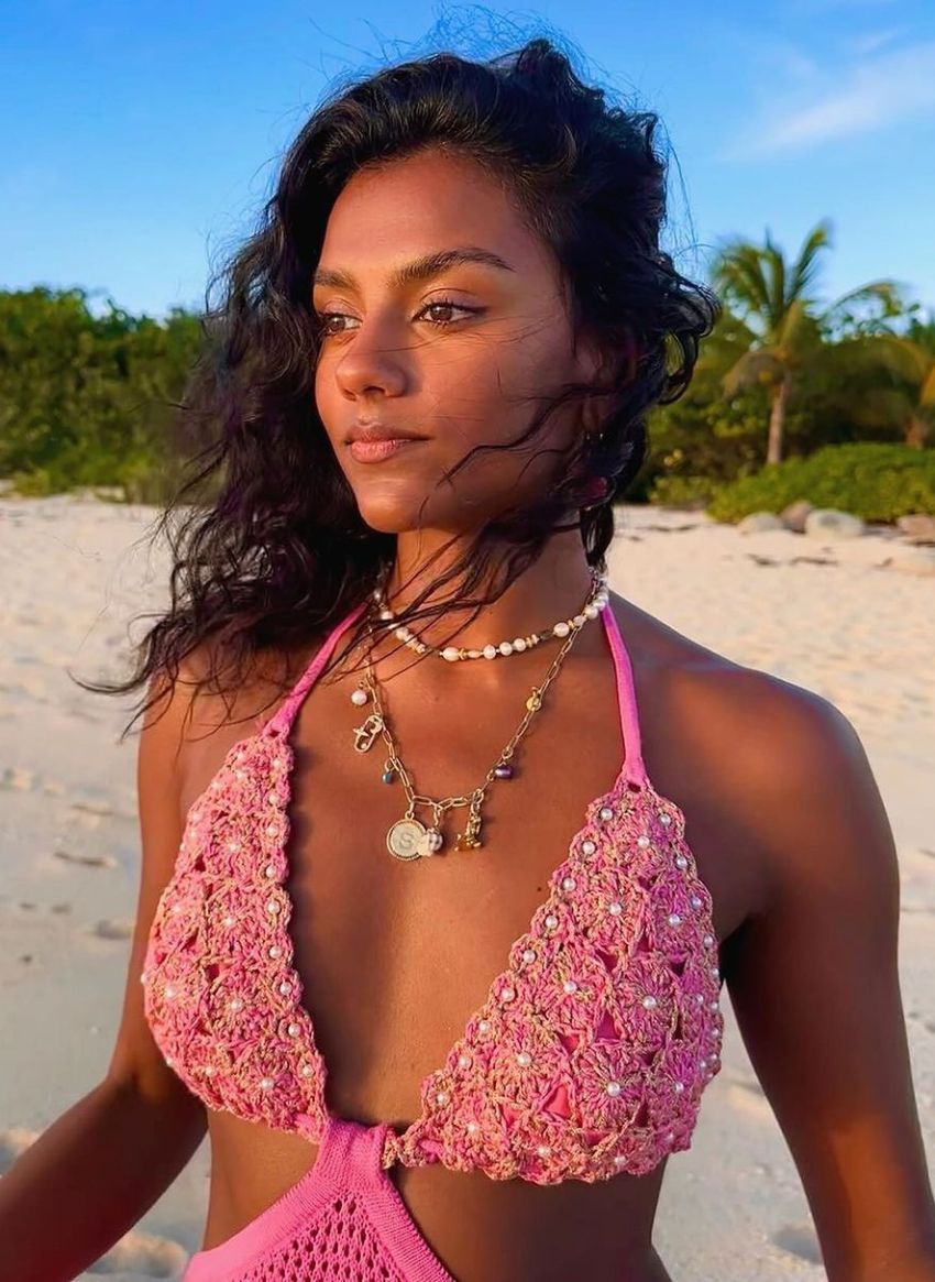 Simone Ashley wearing Alameda Turquesa handcrafted pink crochet dress on the beach, candid photograph