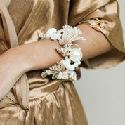 Ariel bracelet on wrist — handcrafted pearl, seashell and natural tassel bracelet with oversized pearl centrepiece, worn against gold fabric, handcrafted in Portugal by Alameda Turquesa