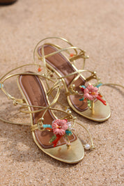 Coralie sandals flat lay, gold leather multi-strap wrap stiletto heels with hand-painted ceramic hibiscus centerpiece, turquoise and coral bead embellishments and pearl detail, handcrafted in Portugal by Alameda Turquesa