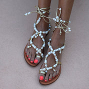 Luz beaded sandals pair view — gold leather flat sandals with hand-applied white pearl straps and lace-up ankle ties, worn on body, handcrafted in Portugal by Alameda Turquesa